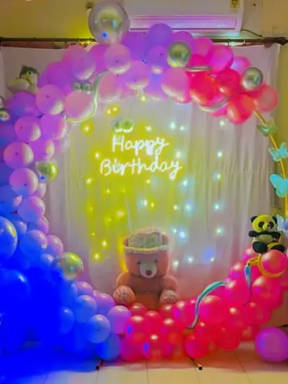 A whimsical and colorful birthday ring setup, perfect for a sweet sixteen or a young-at-heart celebration. The multi-colored pastel balloons, fairy lights, and a central teddy bear create a soft and dreamy party backdrop.
