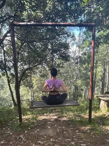 Finding stillness in a seated meditation pose on a swing in the woods. This is a moment of Samadhi, the final limb of Ashtanga yoga, where the mind becomes quiet and absorbed in the present.