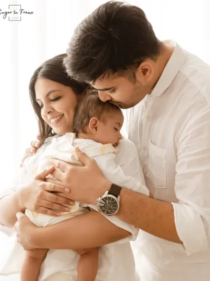A candid family moment filled with love. The parents embrace their newborn baby, creating a warm and secure family hug.