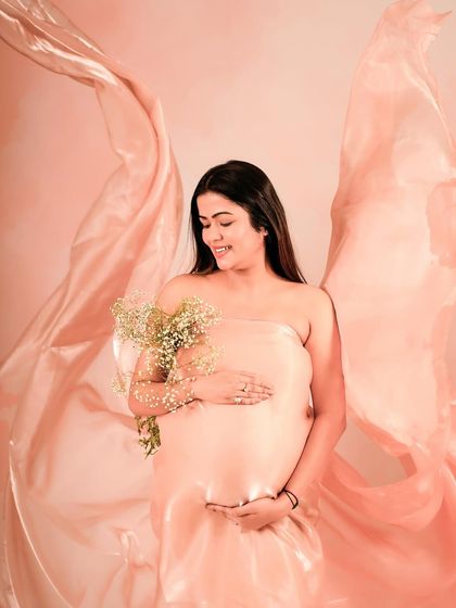 A beautiful portrait with a pink organza drape creating wing-like shapes behind the mother-to-be.