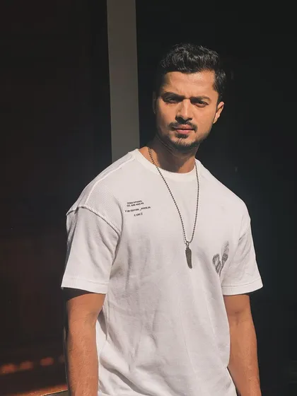 A close-up portrait in a white tee, with the shadows creating a dramatic effect.