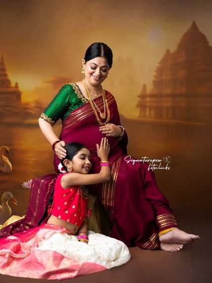 A beautiful family maternity portrait, with an older daughter lovingly touching her mother's belly, set against a classic, artistic backdrop.