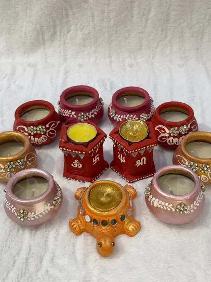 A collection of my hand-painted and decorated wax diyas. I offer them in various styles, including little pots and stands with 'Om' and 'Shri' symbols, to bring auspicious light to your pooja.