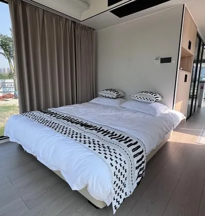 The bedroom area in the Space Capsule E8, featuring a comfortable bed with large windows for immersive views. The design maximizes light and space.