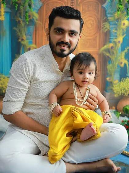 A father's pride holding his little Kanha. These are the moments that blend tradition with family love, creating memories that will be cherished for generations.