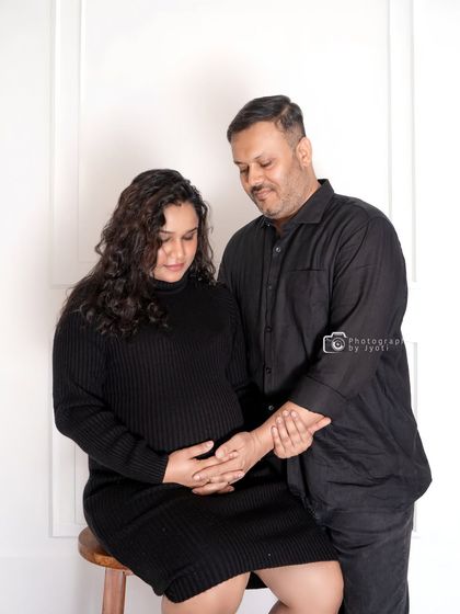 A candid and loving moment captured during a studio session. The couple is dressed in matching black, creating a modern and chic look.