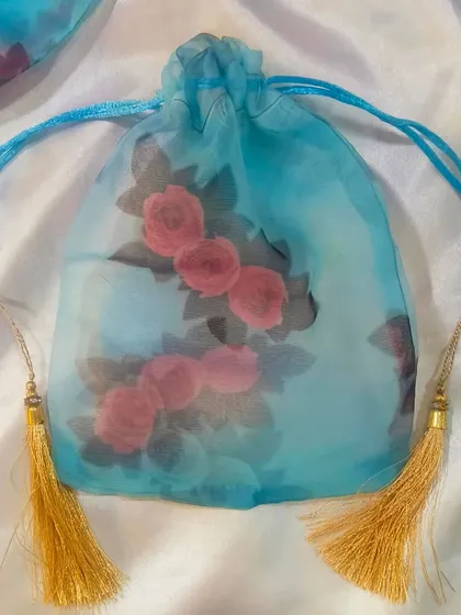 This beautiful blue organza potli bag with a rose print is perfect for giving small gifts or favors.