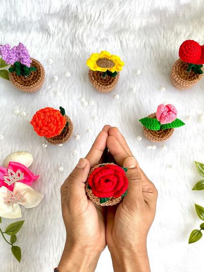 Holding a tiny potted rose, showing how these little creations fit perfectly in the palm of your hand.