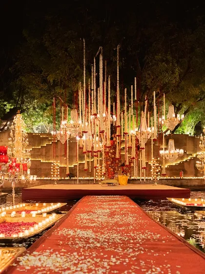 The final, breathtaking view of the floating mandap at Alila Fort Bishangarh. The red aisle, candlelit boats, and dramatic chandelier installation create a scene of unparalleled grandeur.