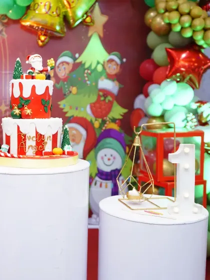 A close-up of a Christmas-themed cake table. Details like the themed cake, marquee number, and decorative props on plinths are essential for a cohesive look.
