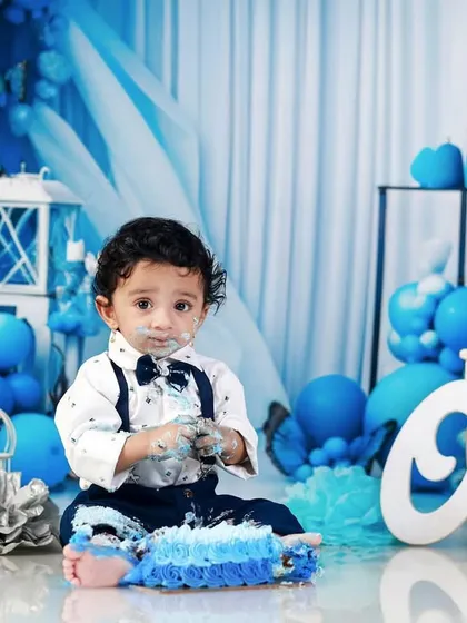 The aftermath of the fun! The birthday boy looks at the camera with cake on his face, surrounded by his blue-themed party decor.