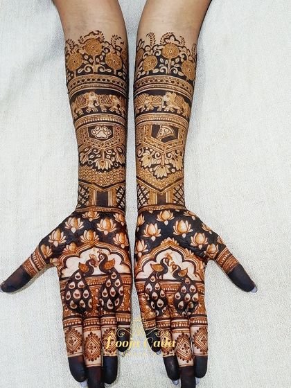 A beautiful bridal henna design featuring peacocks on the palms and a mix of traditional motifs on the arms, creating a look of pure elegance.