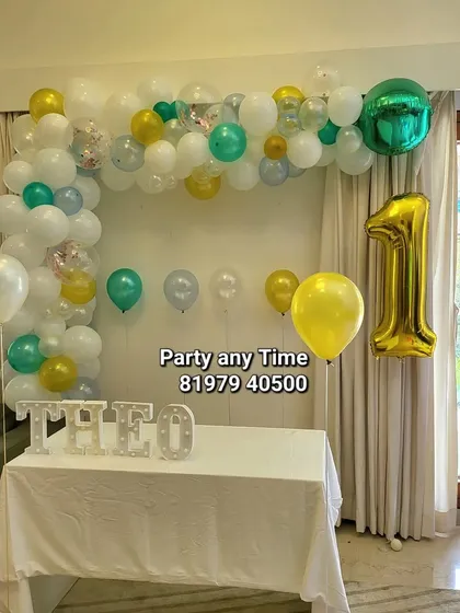 A simple and sweet decoration for a first birthday at home. A small balloon garland over a table with a light-up name sign is perfect for intimate family gatherings.