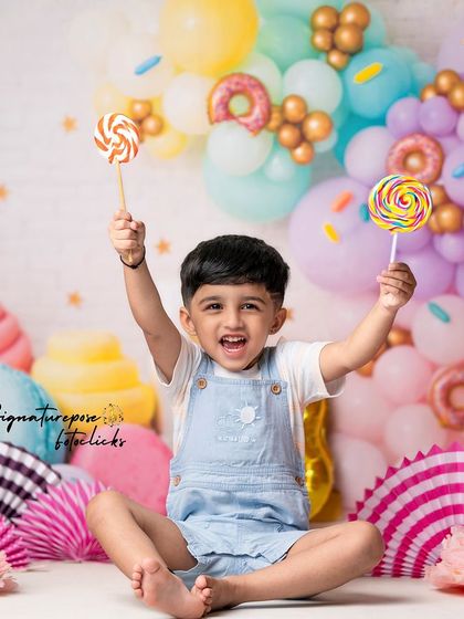 Three years old and sweet as candy! This little boy is having the time of his life in our candy-themed birthday shoot, complete with giant lollipops and a colorful balloon backdrop.