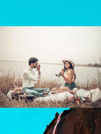A creative shot of the groom-to-be taking a photo of his fiancée during their romantic picnic by the water.