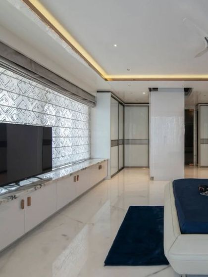 The bedroom's entertainment unit and wardrobe are designed with clean white surfaces and sleek lines, maintaining the room's airy and spacious feel.