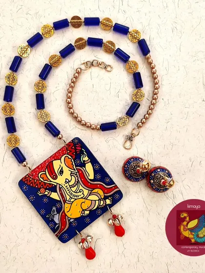 A full view of the Ganesha necklace set, showing how the blue glass beads and brass embellishments complement the hand-painted pendant and jhumkas.