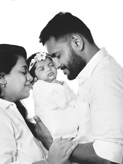 A tender black and white photo of new parents lovingly gazing at their newborn.