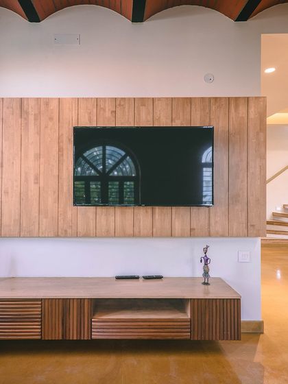 The repetition of the wooden slats on the TV panel and the curves of the jack-arch roof create a subtle, pleasing rhythm.