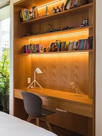 A compact and highly efficient study nook built into a bedroom. We used warm wood for the desk and shelving, with integrated LED lighting under the shelves to create a bright and pleasant workspace.
