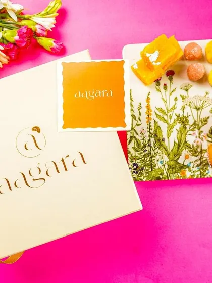 A product shot of a branded gift box next to a platter of Indian sweets, perfect for corporate or festive gifting.