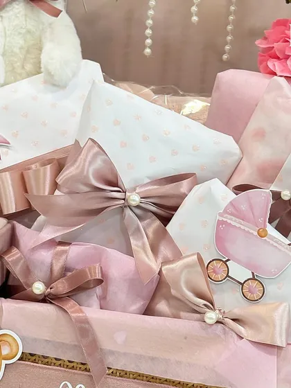 A close-up of the beautifully wrapped presents inside the pink hamper, showing the coordinated paper and ribbons that tie the whole look together.