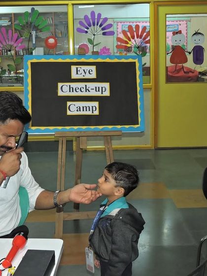 A student receives a careful eye examination from a professional, with his parent looking on. We believe in a transparent and collaborative approach to student health.