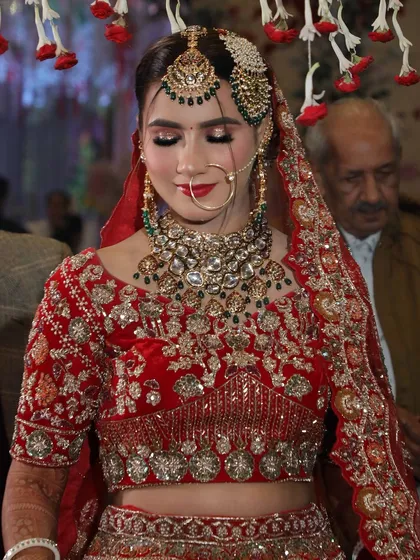 A closer look at the makeup for this bride. The smokey eye and neutral lip color balance the heavy jewelry and ornate red lehenga.