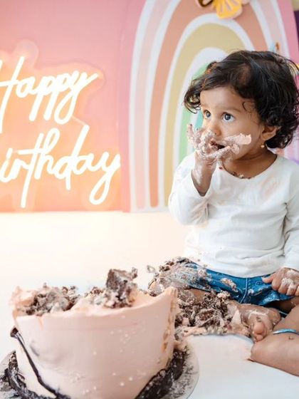 A close-up of the birthday girl with cake on her face, looking completely satisfied with her delicious mess.