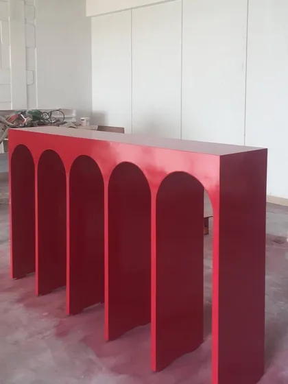 The red console, freshly painted, awaits installation on site. This image captures a moment of excitement as a key design element is ready to be placed in its new home.
