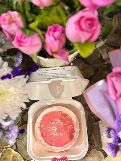 A 'quarter life crisis' bento cake nestled amongst bouquets of pink roses. It’s a fun and stylish way to mark a milestone birthday.