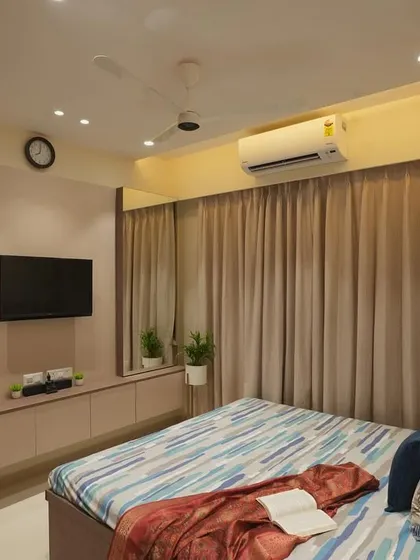 A cozy bedroom with a simple TV unit and warm, ambient lighting.