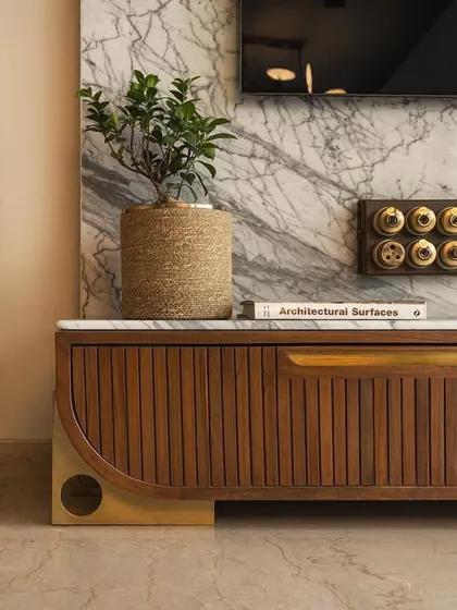 A detail of the living room's custom TV unit, showing the vertical wood grooves, brass accents, and vintage-style switches.