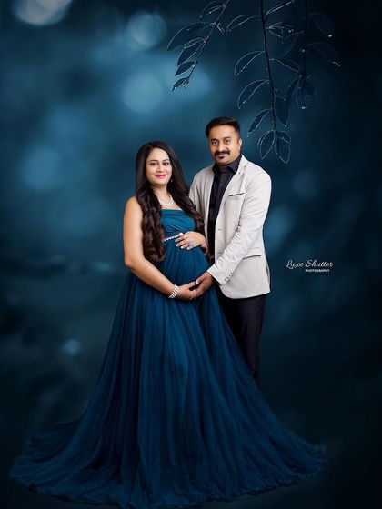 A moody and romantic maternity portrait with a deep blue gown against a painterly blue background. This style is perfect for creating a sophisticated and artistic photograph.