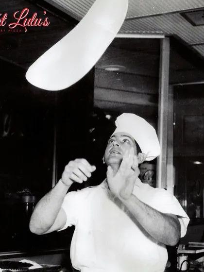 A classic shot of a pizzaiolo tossing dough in the air. It’s a skill that takes practice, and it’s all part of the art of making the perfect pizza.
