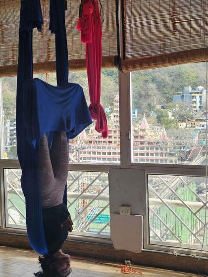 An aerial inversion with a view of the Ganges in Rishikesh. This practice not only strengthens the body but also calms the mind, connecting you to your surroundings.