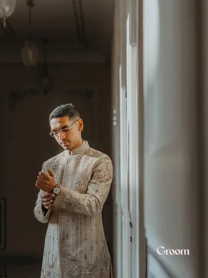 A candid portrait of the groom adjusting his cufflink, captured in soft, natural light.