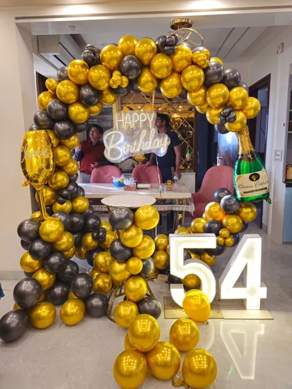 A full shot of the 54th birthday balloon arch, complete with champagne bottle and glass foil balloons for a festive touch.
