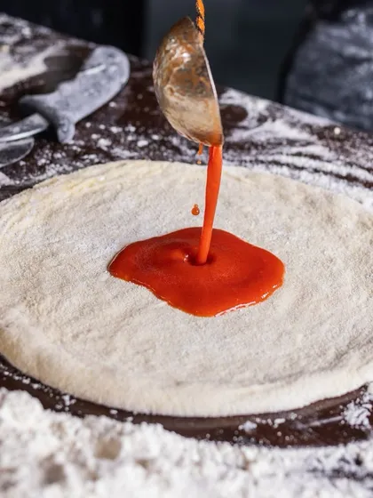 The saucier, the better. A perfect swirl of tomato sauce on our fresh pizza dough.