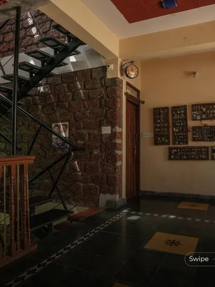 The interior of the Padmaja Rao Residence, featuring a stone accent wall, a dark stone floor, and a collection of traditional artifacts.
