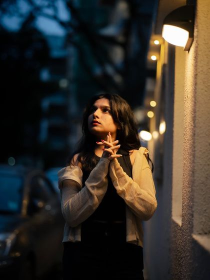 A more contemplative pose from the same series. The way the light catches her hands and face creates a gentle, almost painterly effect.