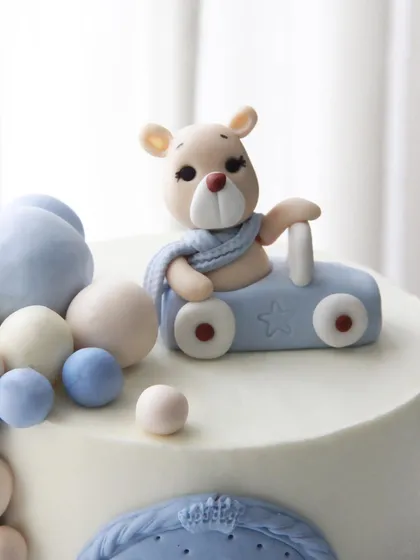 A close-up of the cute teddy bear and car topper on this minimalist baby naming ceremony cake.