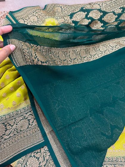 The plain dark green blouse piece for the lime green Kadi georgette saree, featuring a simple yet elegant woven border.