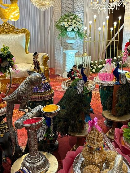 A close-up of the offering table with silver bird props and a Ganesha idol on a betel leaf.