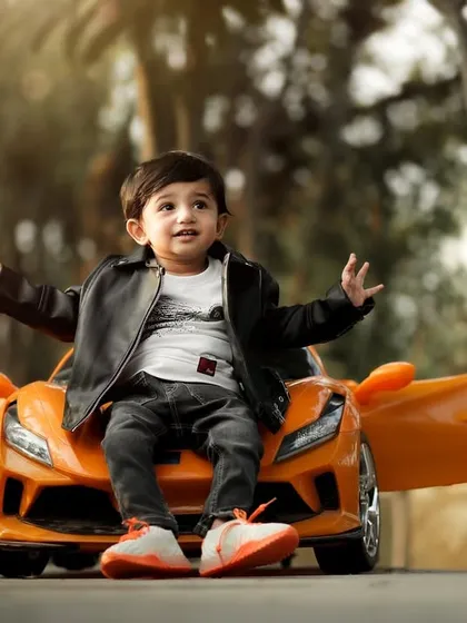 What a pose. This little boy is full of confidence and charm as he sits on the hood of his toy sports car, ready for his close-up.
