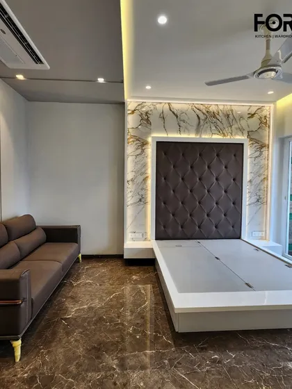 Here, a classic diamond-tufted headboard in dark fabric is framed by a stunning marble-effect feature wall with warm backlighting. The sleek, low-profile bed frame is designed with a lift-up mechanism for convenient under-bed storage.