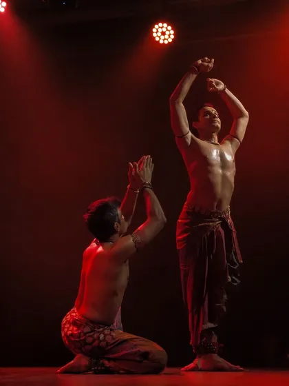 A dramatic scene from 'ATAH' under red lighting, highlighting the intensity of the performance.