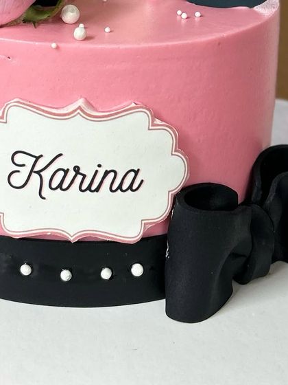 A close-up of the personalized name plaque and fondant bow on the makeup-themed cake.