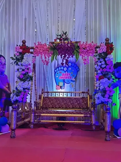Another example of a gender reveal theme for a Dohale Jevan. This setup uses a white curtain backdrop with crystal strings, making the colorful flowers, balloons, and character cutouts stand out.