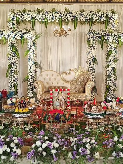 A wide view of an engagement stage with white and blue floral arches, creating a serene and elegant atmosphere for the ceremony.